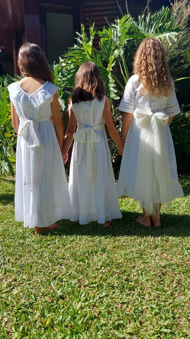 Tres nenas de espaldas en el jardín con vestidos de comunión Blanca Aurora